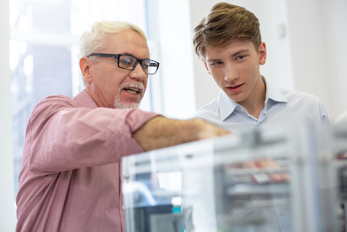 A professional man with glasses teaching a student to work on a device